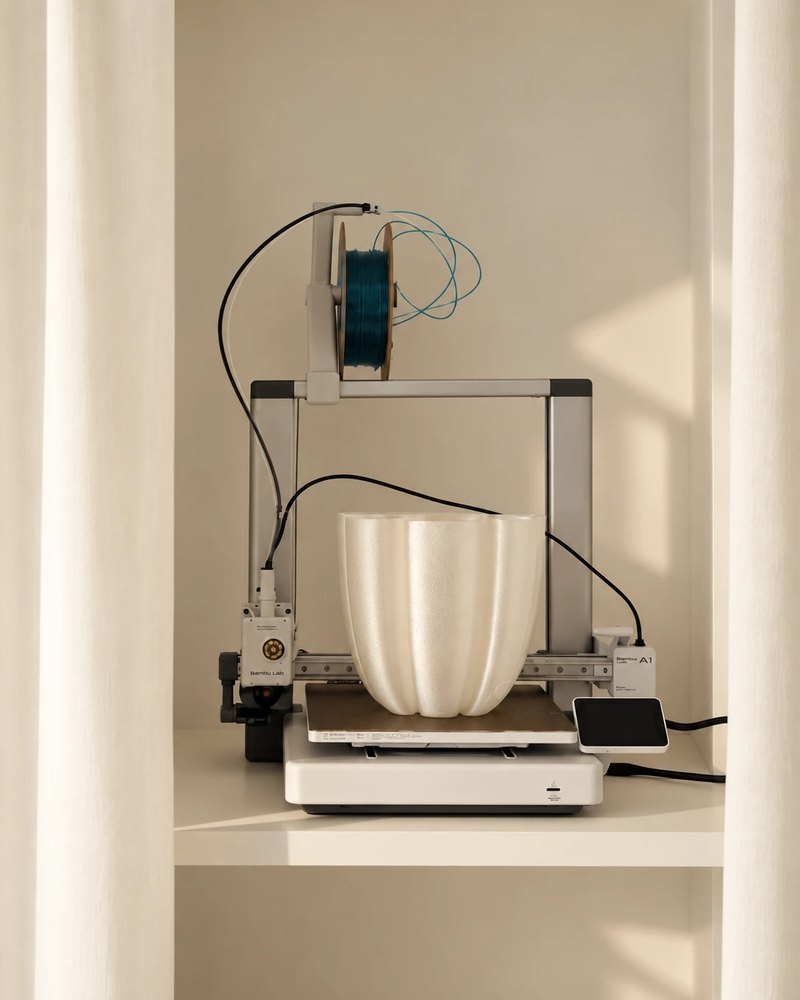 A Mur Mur lamp shell finished on the studio printer, between linen curtains